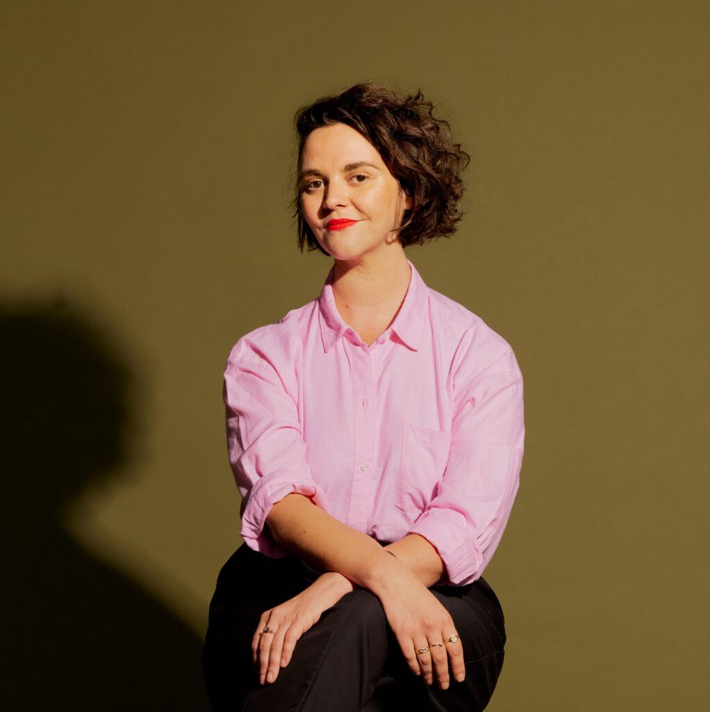 Liz Nowell sitting on a chair in a pink shirt. Image credit Natalie Piserchio